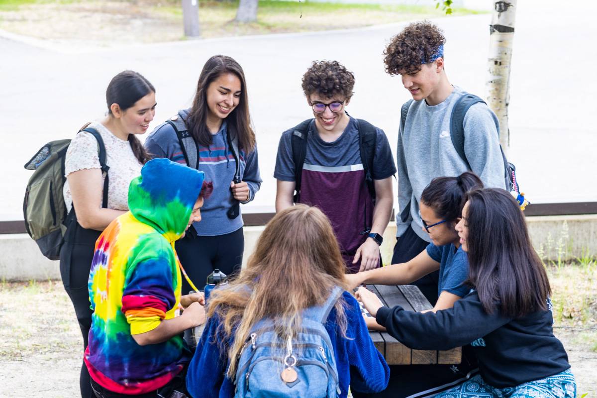 Ͷע Students gather at a picnic table outside the Wood Center on the Fairbanks Troth Yeddha' campus